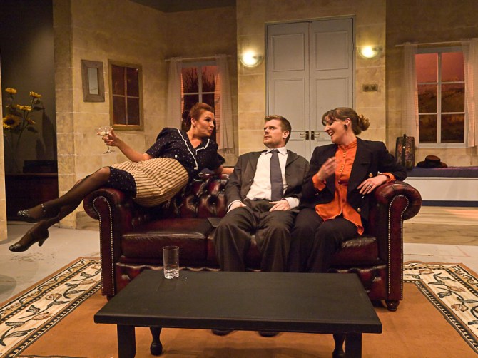 Suzette (Rhiannon Leach) introduces herself to Jacqueline (Cat Jardine) much to the discomfort of Robert (Mark Briggs).